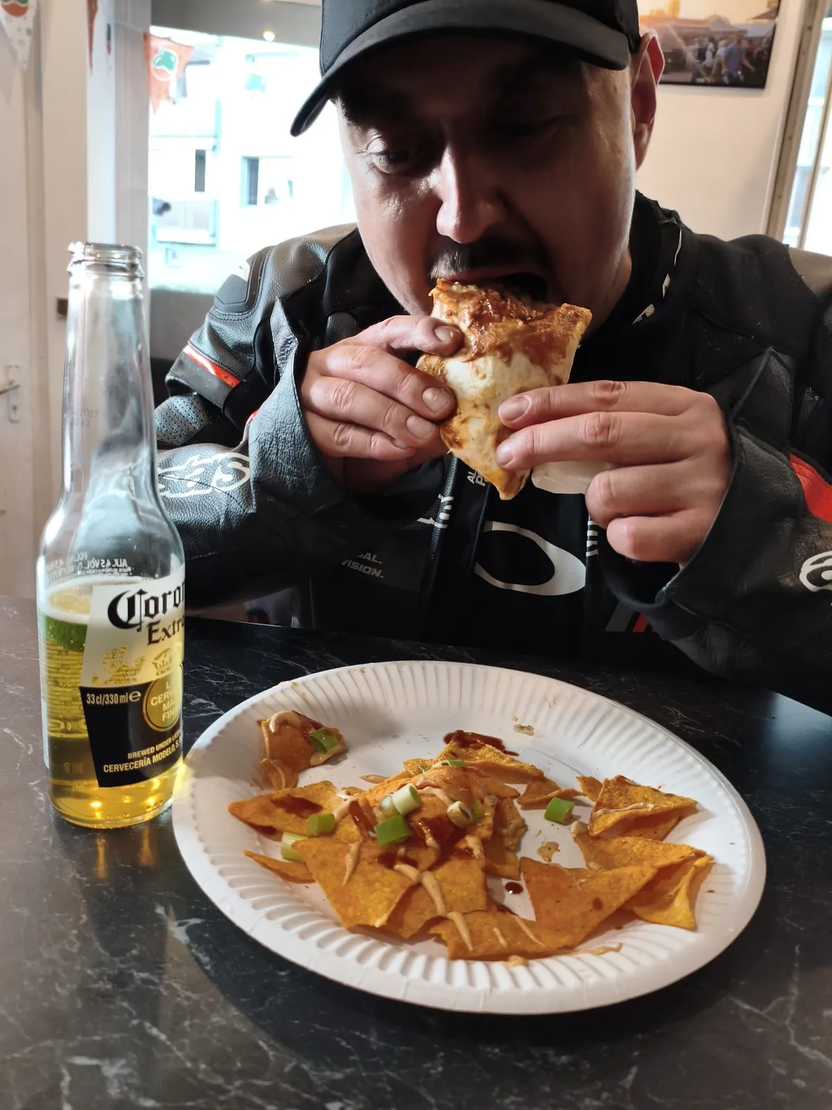 Host si pochutnává na quesadille, vedle nachos a Corona Extra
