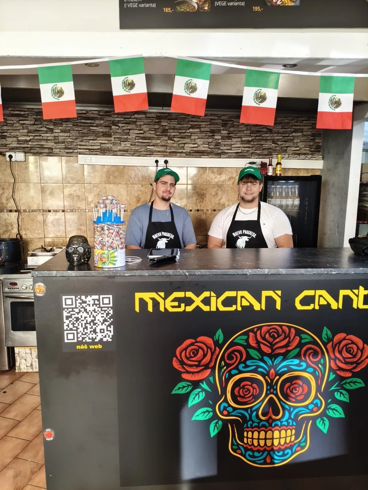Kuchaři Nomad Snacks za pultem Mexican Cantina pod mexickými vlajkami